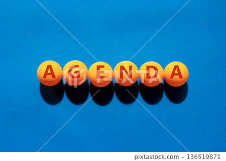 Agenda symbol. Concept word Agenda on beautiful orange table tennis ping pong balls. Beautiful blue background. Business agenda concept. Copy space. Agenda symbol. Concept word Agenda on beautiful orange table tennis ping pong balls. Beautiful blue background. Business agenda concept. Copy space. 136519871
