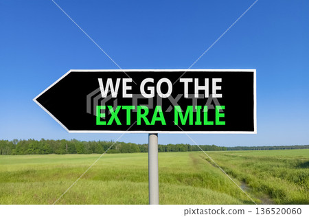 Support, help we go the extra mile symbol. Concept words We go the extra mile on beautiful black road sign. Beautiful blue sky green field background. Business we go the extra mile concept Copy space 136520060