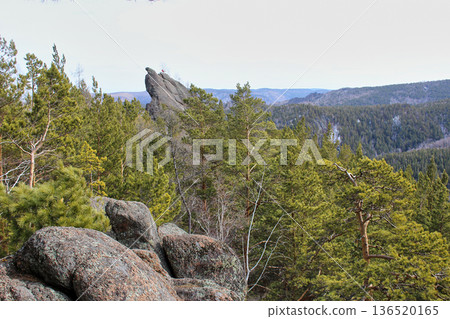 Mountain landscape with conifer forest and rock formations under a cloudy sky. Nature backdrop for travel, tourism, and outdoor adventure concept. Stolby Krasnoyarsk, Malyy Berkut rock Mountain landscape with conifer forest and rock formations under a cloudy sky. Nature backdrop for travel, tourism, and outdoor adventure concept. Stolby Krasnoyarsk, Malyy Berkut rock 136520165