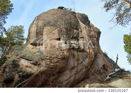 Large natural rock formation with rugged texture against a clear sky. Outdoor nature landscape for travel and adventure themes. Stolby park, Krasnoyarsk. Climbing area 136520167