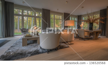 A spacious living room with wooden floors and large windows overlooking a beautiful forest in a private house. 136520568