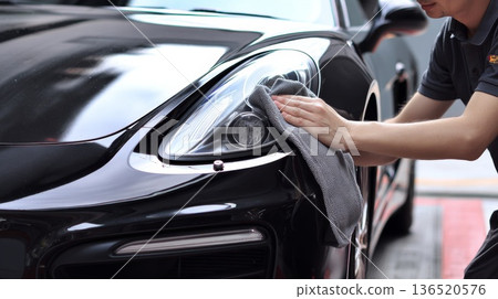 A man cleaning black car with microfiber cloth, car detailing A man cleaning black car with microfiber cloth, car detailing 136520576