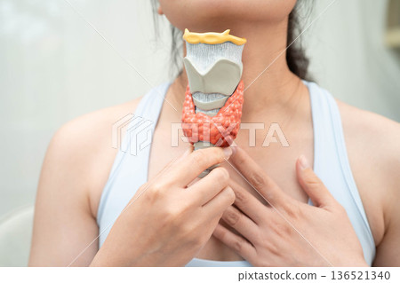 Hyperthyroidism, Overactive Thyroid, Thyroid Lymphoma, Asian woman with thyroid gland human anatomy model. Hyperthyroidism, Overactive Thyroid, Thyroid Lymphoma, Asian woman with thyroid gland human anatomy model. 136521340