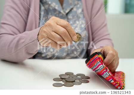 Asian senior or elderly old lady woman holding counting coin money in bag. Poverty, saving problem in retirement. 136521343