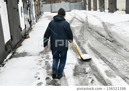 A man shovels snow with a shovel. Cleaning, winter, season, street, work A man shovels snow with a shovel. Cleaning, winter, season, street, work 136521386