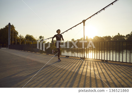 Young woman jogging on riverside bridge at sunrise, outdoor fitness in park Young woman jogging on riverside bridge at sunrise, outdoor fitness in park 136521860