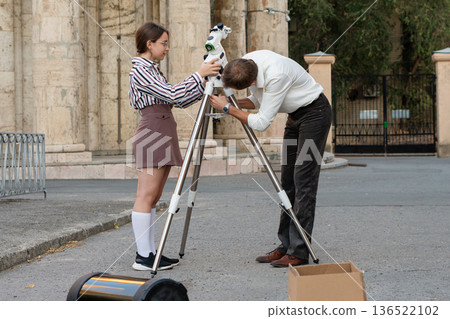 Girl and teacher tighten telescope mount together Girl and teacher tighten telescope mount together 136522102
