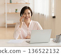 A woman talking on her smartphone while working from home 136522132