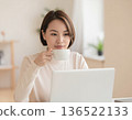A woman drinking coffee while looking at a computer screen 136522133