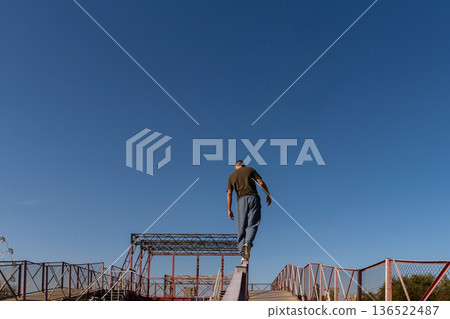 Man walks away balancing on rail in urban parkour zone Man walks away balancing on rail in urban parkour zone 136522487