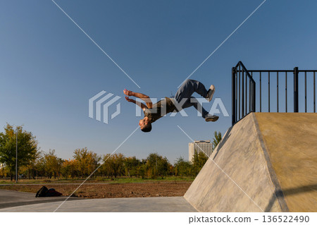 Freerunner mid-air during backflip from concrete park structure 136522490