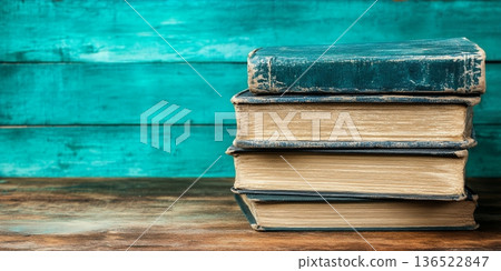 Stack of vintage books on rustic wooden table with turquoise background 136522847