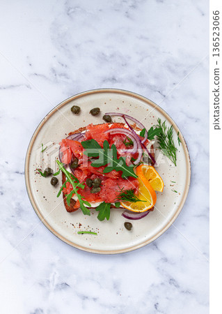 sandwich with freshly smoked salmon, on black bread, with cottage cheese, with herbs and red onions, capers and pieces of citrus fruits, on a marble countertop, breakfast, no people, sandwich with freshly smoked salmon, on black bread, with cottage cheese, with herbs and red onions, capers and pieces of citrus fruits, on a marble countertop, breakfast, no people, 136523066