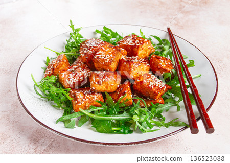 fried salmon slices, teriyaki with sesame seeds, with arugula salad, top view, 136523088