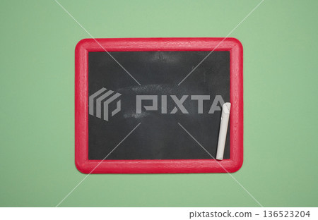 Blank chalkboard in a pink wooden frame, white chalk lying on the right, green background Blank chalkboard in a pink wooden frame, white chalk lying on the right, green background 136523204