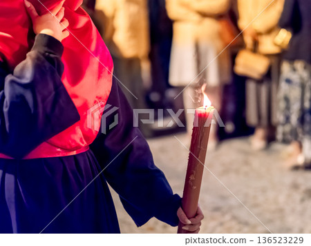Detailed view of a hand holding a large lit candle in a religious procession Detailed view of a hand holding a large lit candle in a religious procession 136523229