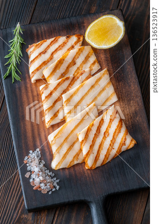 Grilled squid steaks with rosemary and lemon on dark wooden cutting board Grilled squid steaks with rosemary and lemon on dark wooden cutting board 136523917