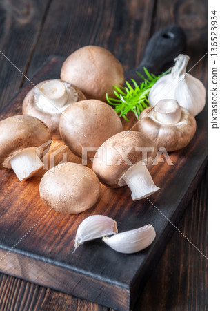 Raw brown champignon mushrooms with garlic and rosemary on rustic wooden board Raw brown champignon mushrooms with garlic and rosemary on rustic wooden board 136523934