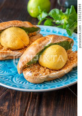 Authentic Vada Pav Indian street food with spicy chutney on rustic wooden background 136523944