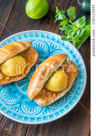 Authentic Vada Pav Indian street food with spicy chutney on rustic wooden background 136523945