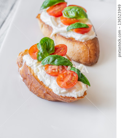 Gourmet bruschetta with stracciatella cherry tomatoes basil and balsamic on bright rustic background 136523949