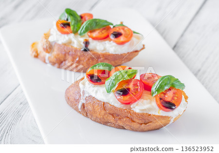 Gourmet bruschetta with stracciatella cherry tomatoes basil and balsamic on bright rustic background Gourmet bruschetta with stracciatella cherry tomatoes basil and balsamic on bright rustic background 136523952