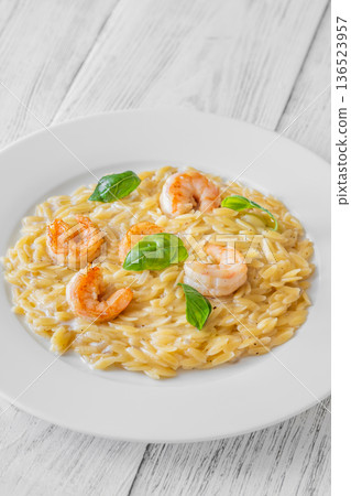 Creamy orzotto pasta topped with grilled prawns and fresh basil on rustic wooden table Creamy orzotto pasta topped with grilled prawns and fresh basil on rustic wooden table 136523957