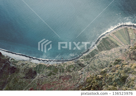 Film toned view of terraced fields descending to a calm sea, rocky shore textures in soft light Film toned view of terraced fields descending to a calm sea, rocky shore textures in soft light 136523976