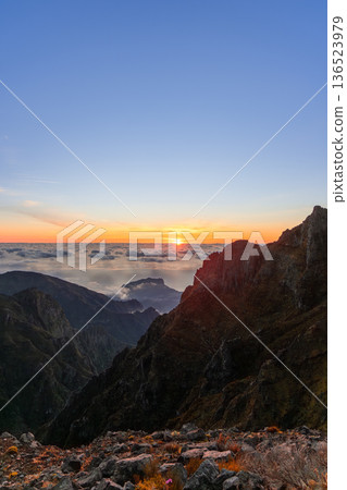 Sunrise above a sea of clouds at Pico do Arieiro, Madeira, as warm light reveals volcanic ridges Sunrise above a sea of clouds at Pico do Arieiro, Madeira, as warm light reveals volcanic ridges 136523979