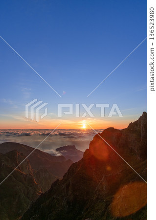 Sunrise over cloud sea at Pico do Arieiro, Madeira, bright sun flare lights steep ridges, vertical 136523980