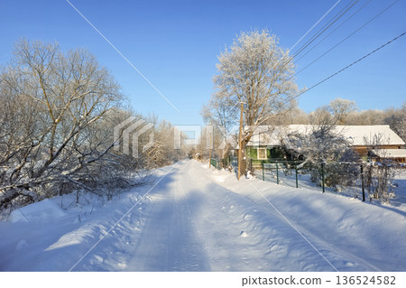 A village in winter. A snow-covered road through the village. 136524582