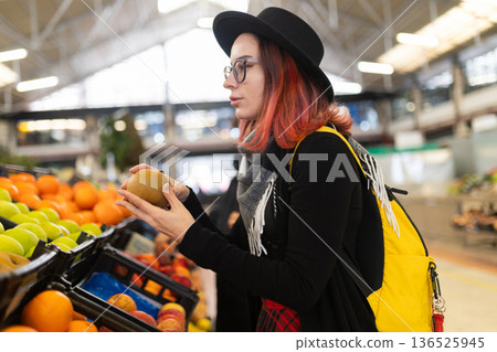 Woman buying fresh kiwi fruit at grocery market 136525945