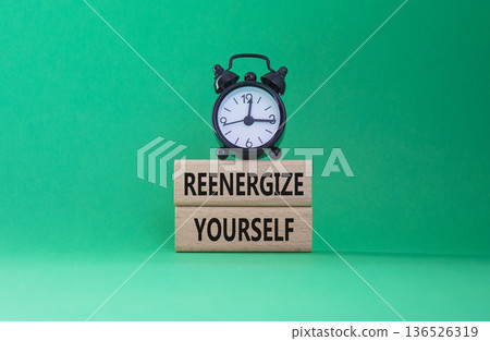 Reenergize yourself symbol. Concept words Reenergize yourself on wooden blocks. Beautiful green background with alarm clock. Mindfulness and Reenergize yourself concept. Copy space. 136526319