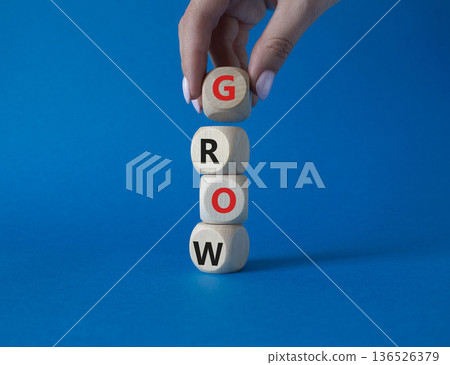 Grow symbol. Concept word Grow on wooden cubes. Beautiful blue background. Businessman hand. Business and Grow concept. Copy space. 136526379