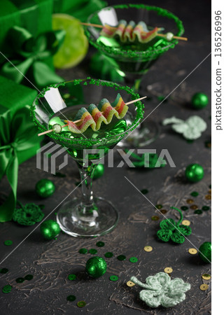 Green Cocktails with Rainbow Candy, shamrocks, Gifts and Confetti. Festive St. Patricks Day Celebration Still Life 136526996