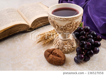 Holy communion elements with bible, chalice, and grapes 136527058