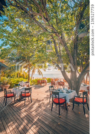 Beach resort outdoors restaurant tables chairs sunset luxury relaxing vibes 136527759