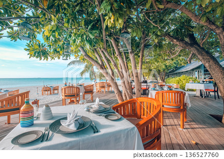 Luxury beach resort dining table set outdoor restaurant chairs sunset vibes 136527760