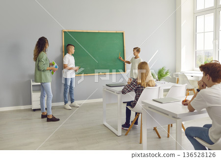 Students Answering At Chalkboard During Lesson Students Answering At Chalkboard During Lesson 136528126