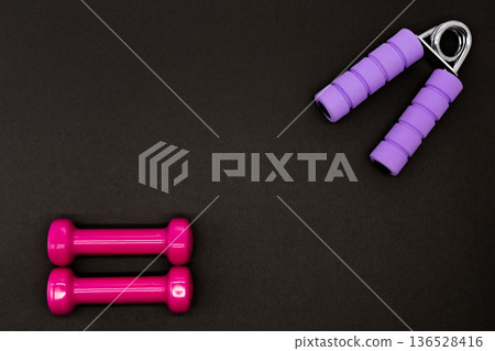 Dumbbells and hand grips on a black background 136528416