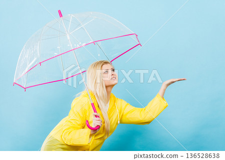 Woman wearing raincoat holding umbrella checking weather Woman wearing raincoat holding umbrella checking weather 136528638