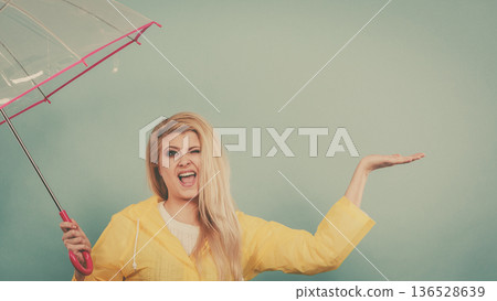 Woman wearing raincoat holding umbrella checking weather Woman wearing raincoat holding umbrella checking weather 136528639