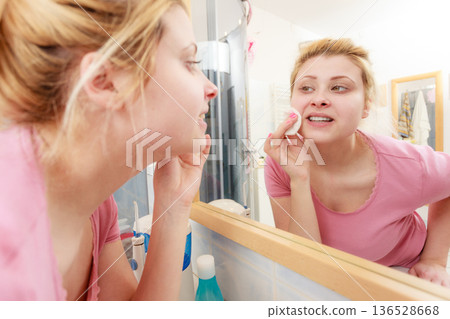 Woman using cotton pad to remove make up 136528668