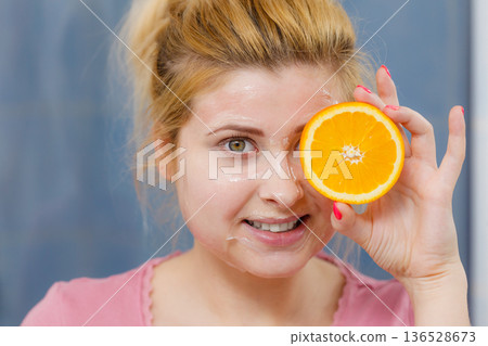 Woman having gel mask on face holding orange Woman having gel mask on face holding orange 136528673