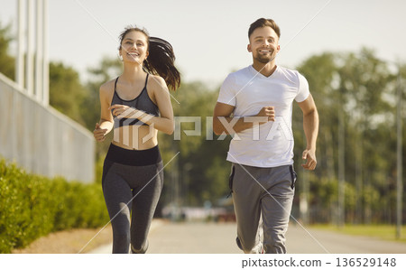 Healthy jogging of runners couple in summer park, happy people running together with smiles 136529148