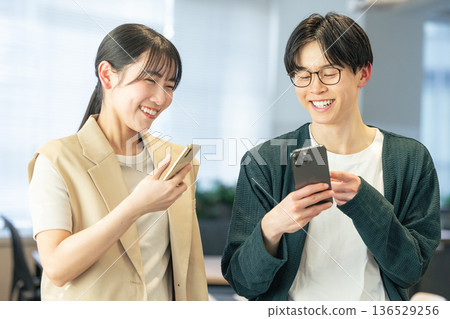 Men and women using smartphones in the office Men and women using smartphones in the office 136529256