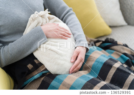 一位血液循環不良的女士正在使用熱水袋 一位血液循環不良的女士正在使用熱水袋 136529391