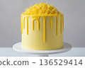 High-resolution studio photography of a single-tier lemon drip cake topped with an abundance of fresh lemon zest curls. 136529414