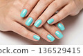 A professional close-up of a woman's hands featuring a flawless manicure with almond-shaped nails.  136529415