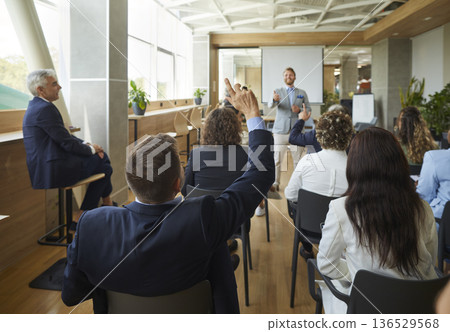 People colleagues raising hands to ask questions during business meeting in office. 136529568